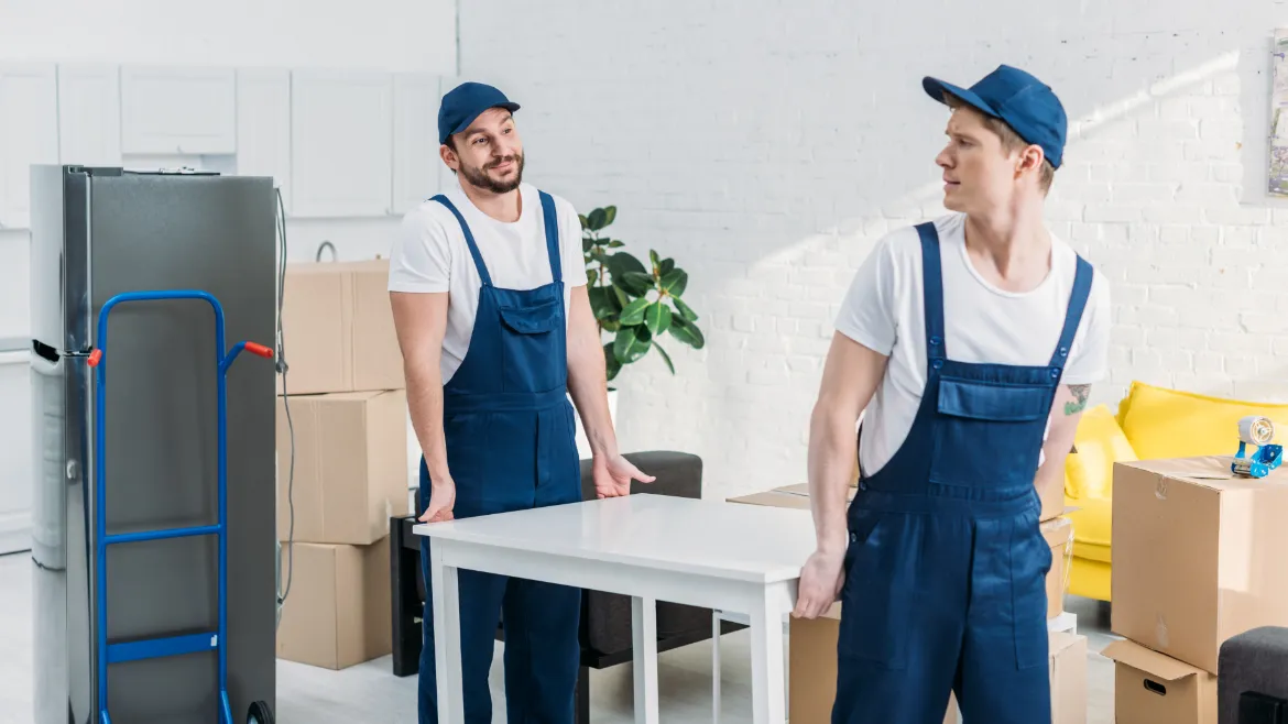 Full-Service Moving Companies: What Services Do They Offer? two movers in uniform transporting table in apartm 2021 09 14 23 16 05 utc