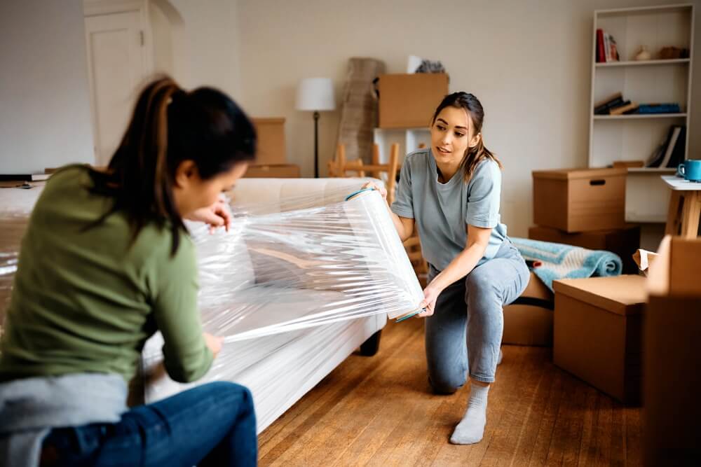 Furniture Moving Tips — A Comprehensive Guide young women wrapping furniture on their moving day 2023 11 27 05 15 08 utc