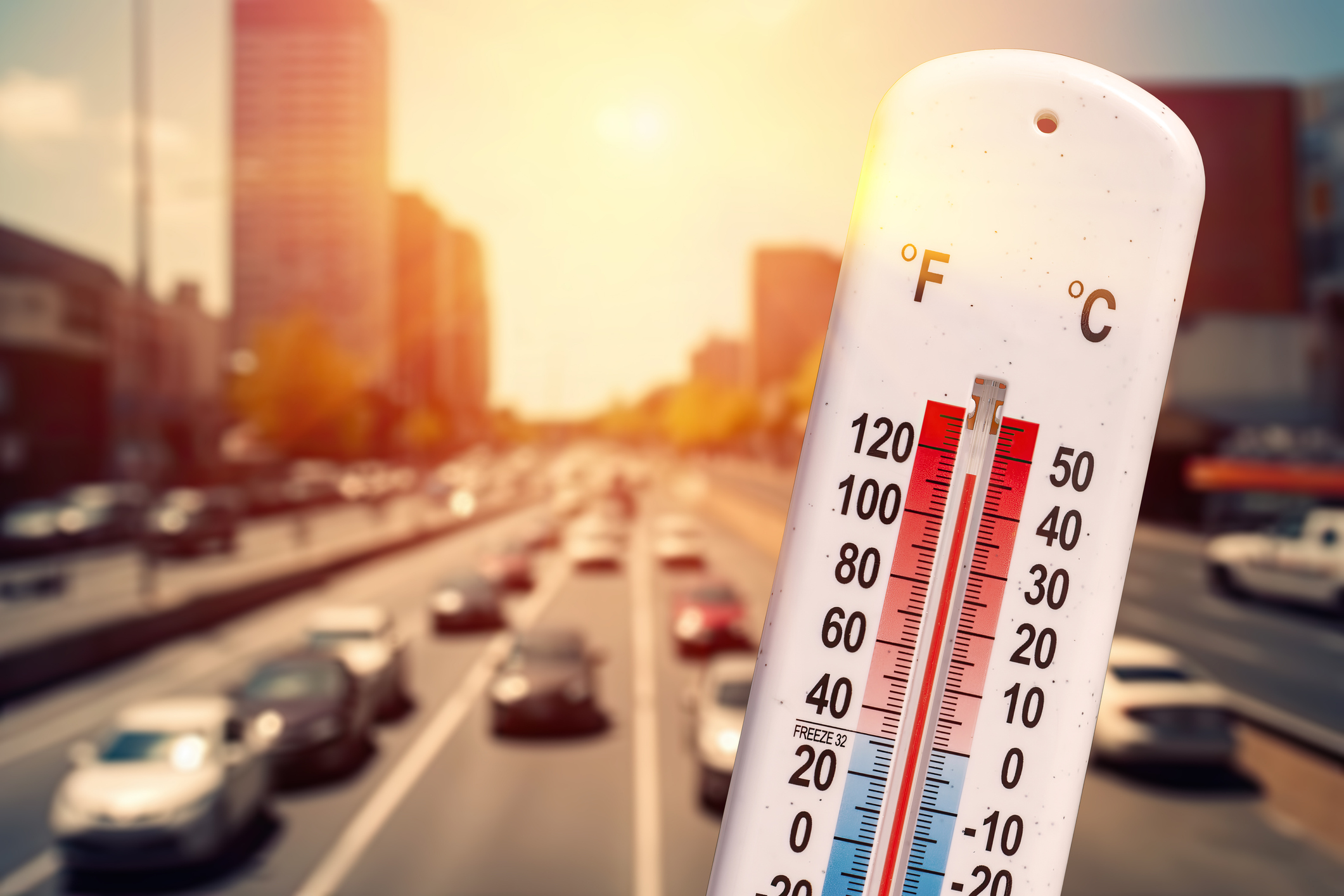 Thermometer in front of cars and traffic during Los Angeles heatwave.