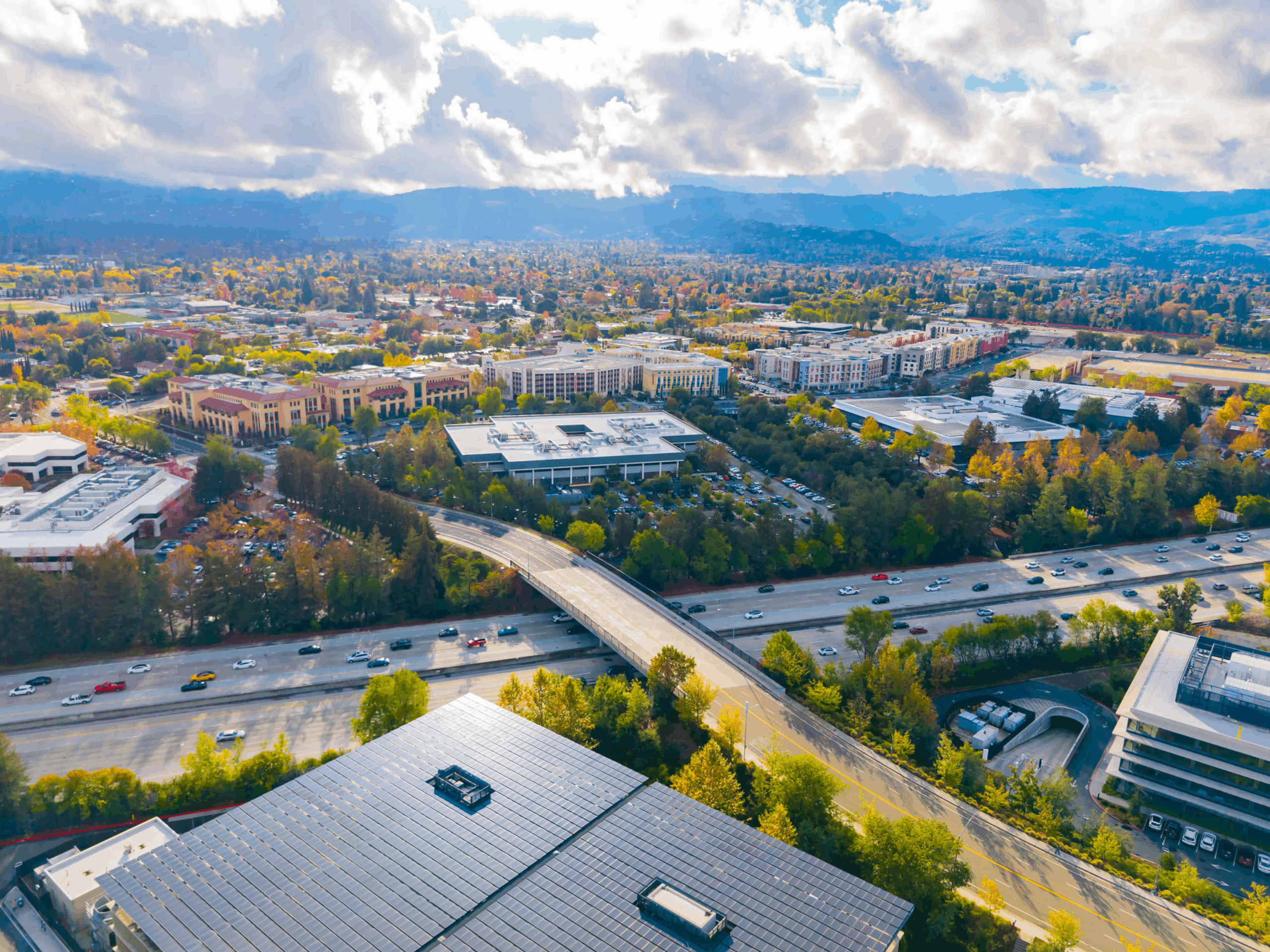 Scenic aerial view of Cupertino, California landscape on a sunny day with urban neighborhoods and surrounding greenery.